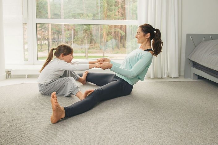Mother and daughter making gymnastics and stretching at home. Family healthy lifestyle concept.