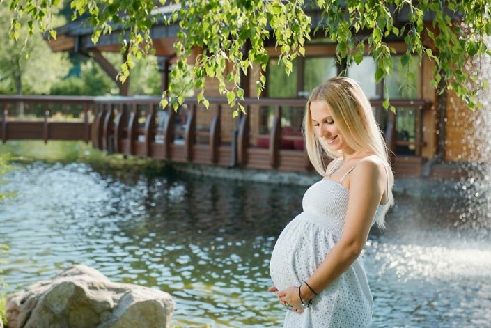 Beautiful pregnant woman on the walk outdoor near the house with lake